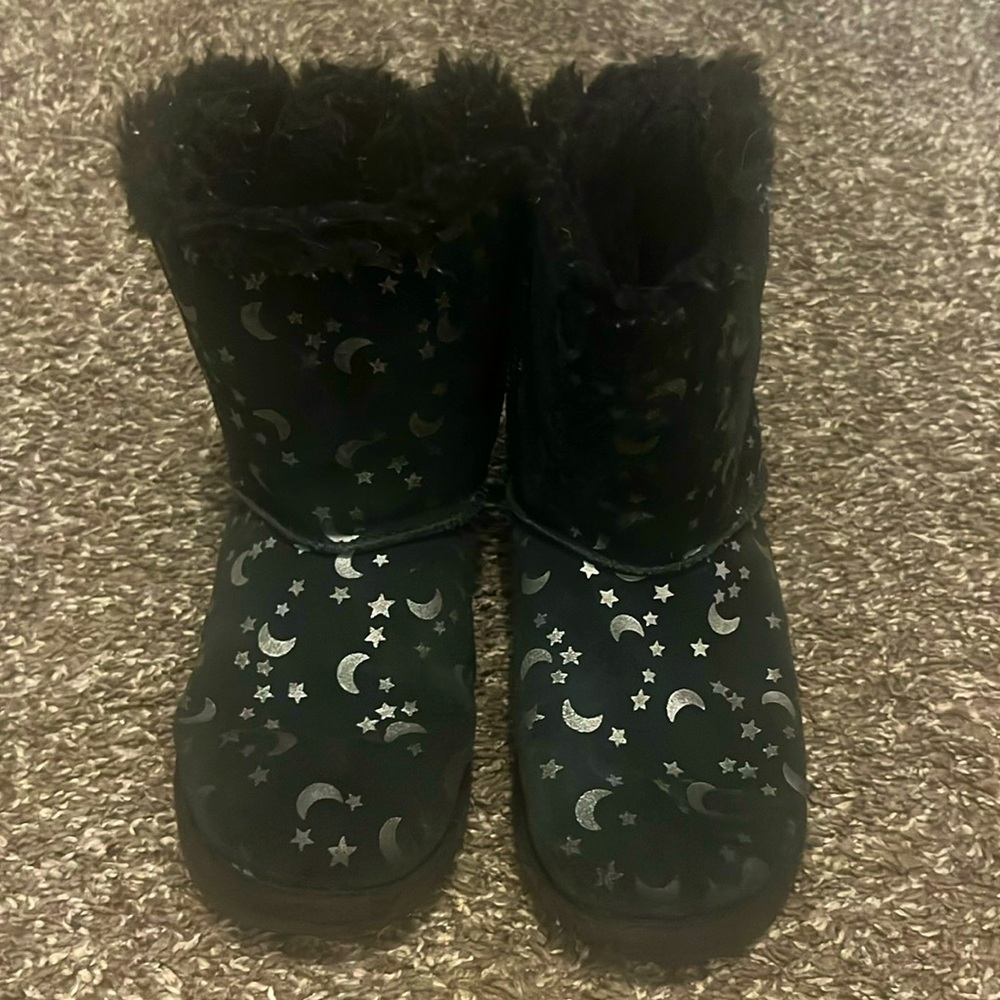 Girls’ black with silver star Uggs. Bow detail on back.